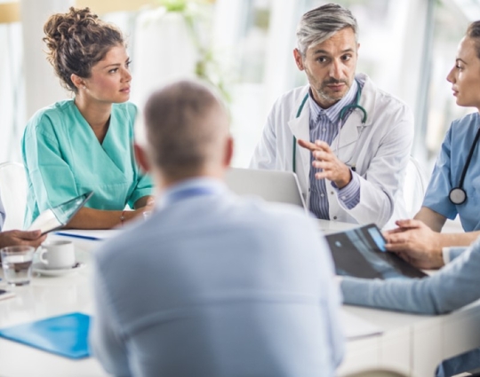 doctor and his colleagues talking to team of business people on a meeting in the hospital.
