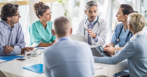 doctor and his colleagues talking to team of business people on a meeting in the hospital.