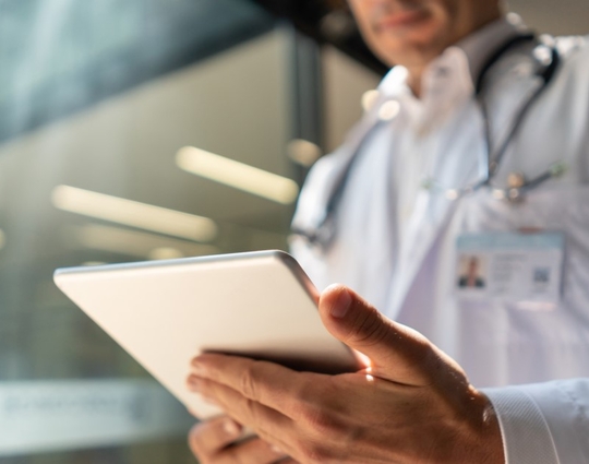 Male doctor at the hospital looking at a medical chart on tablet
