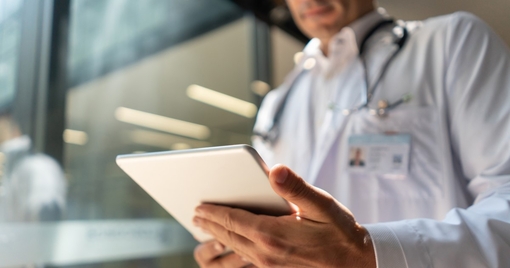 Male doctor at the hospital looking at a medical chart on tablet